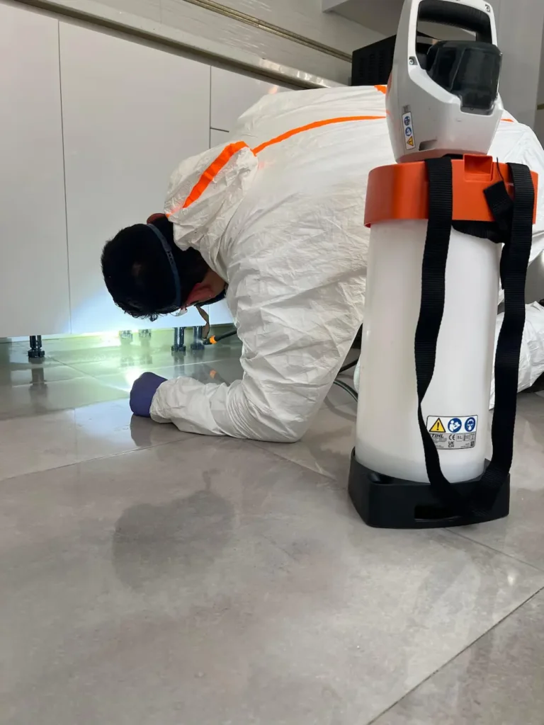 Aplicación del tratamiento contra cucarachas debajo del armario de la cocina